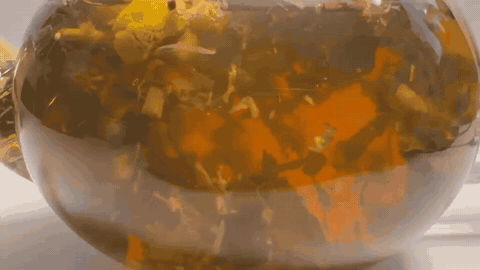 Chamomile blossoms steeping in a glass teapot